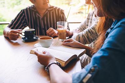 A group of people enjoyed talking, reading and drinking coffee together in cafe